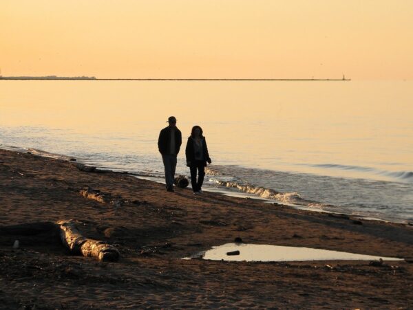 Two people walking on a beach at sunset