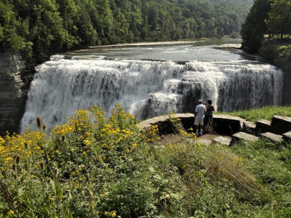 Two people standing on a platform overlooking a waterfall