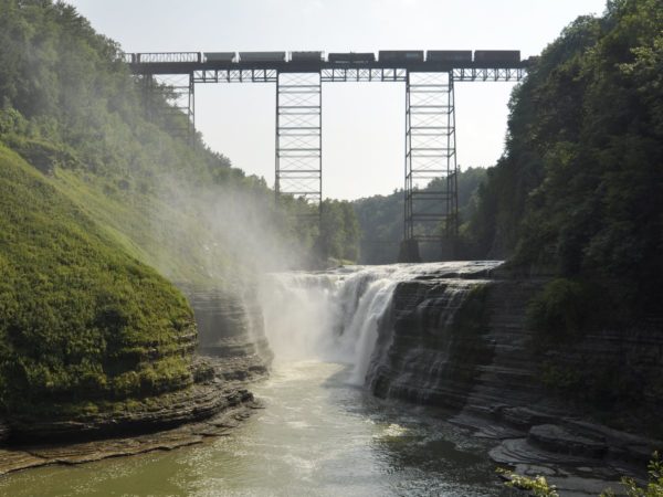A gorge with an overarching railroad bridge and train cars