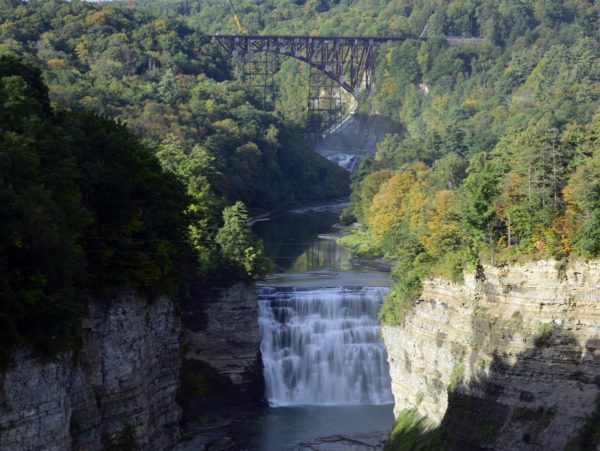 A waterfall with an overarching railroad bridge