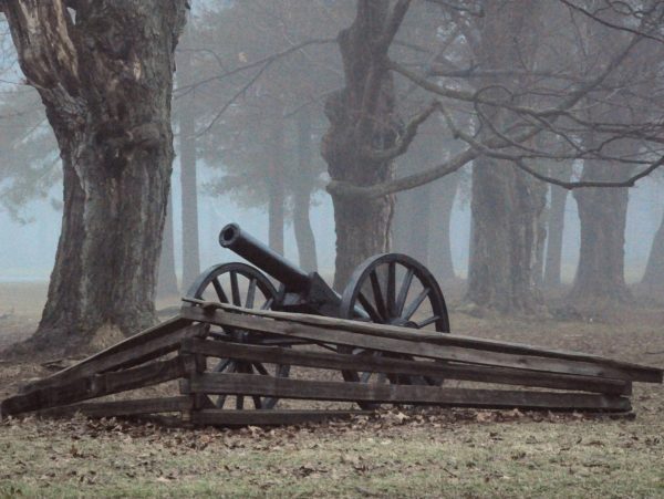 An old iron military canon and wooden barrier