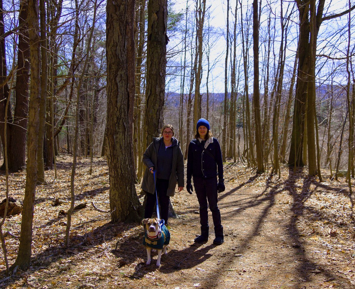 Two people on a trail walking their dog