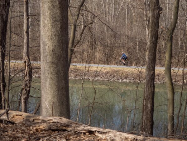 A person riding a bike on a path with a canal in the foreground