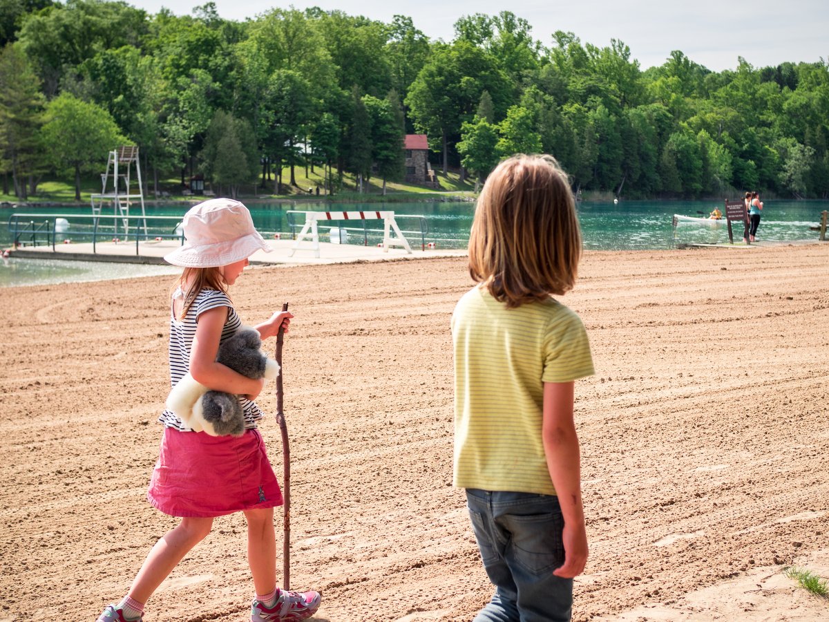 Two children walking on a sandy lakeside beach