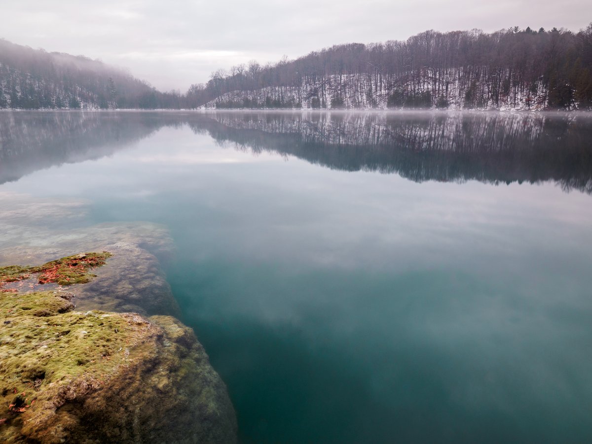 A blue lake with snow covered hills