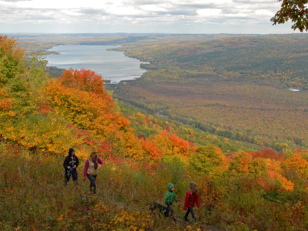 People hiking on a trail in autumn with a lake in the distance