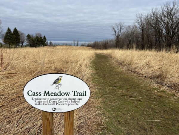 A trailhead for a nature preserve with a lake in the distance