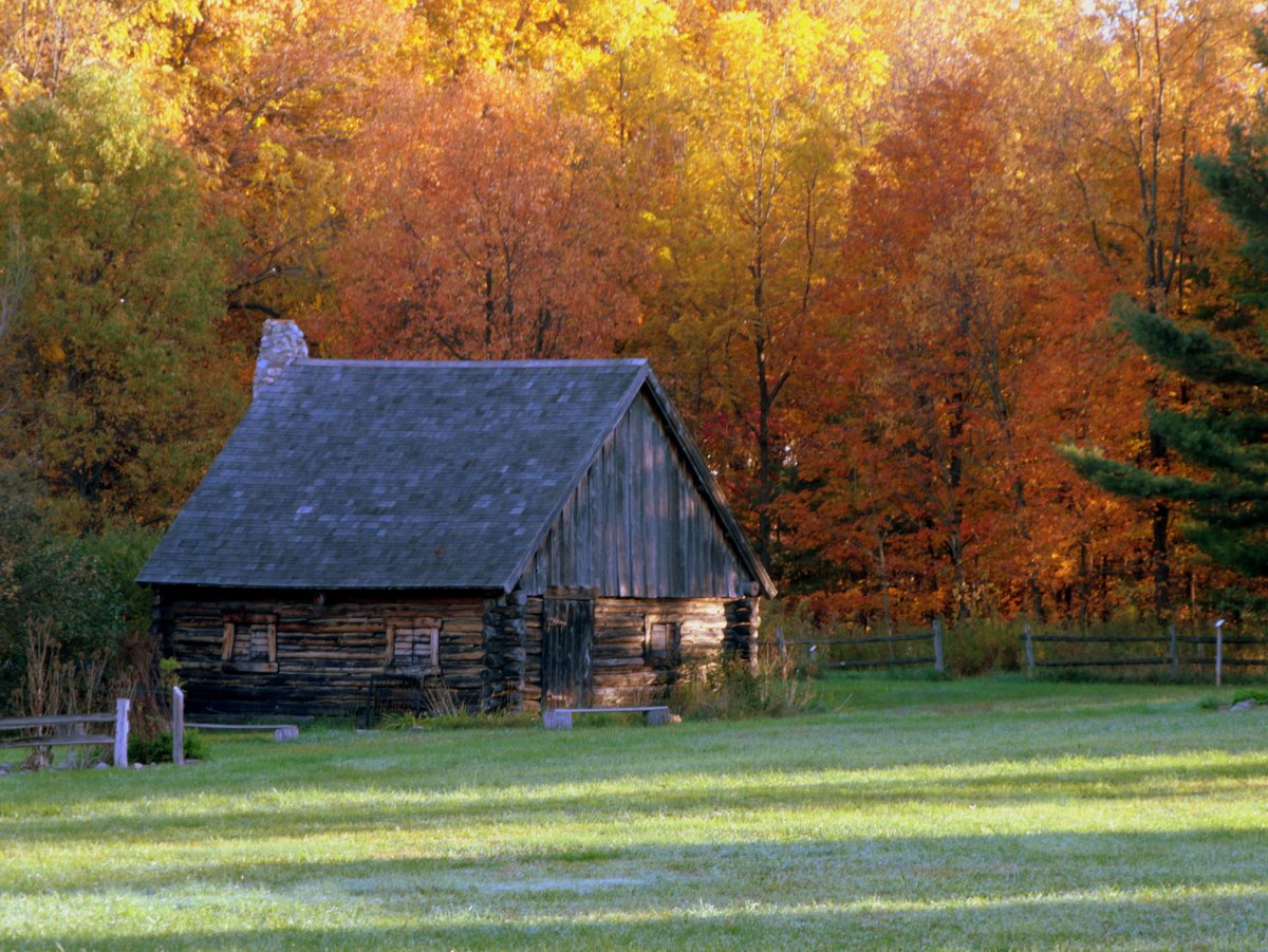 An historic wooden building surrounded by trees with red and orange leaves