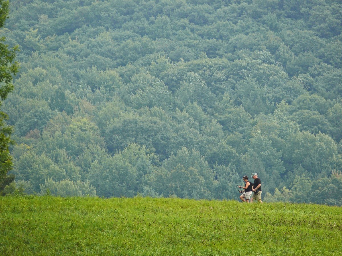 Two people on a hike with a big green hill in the background
