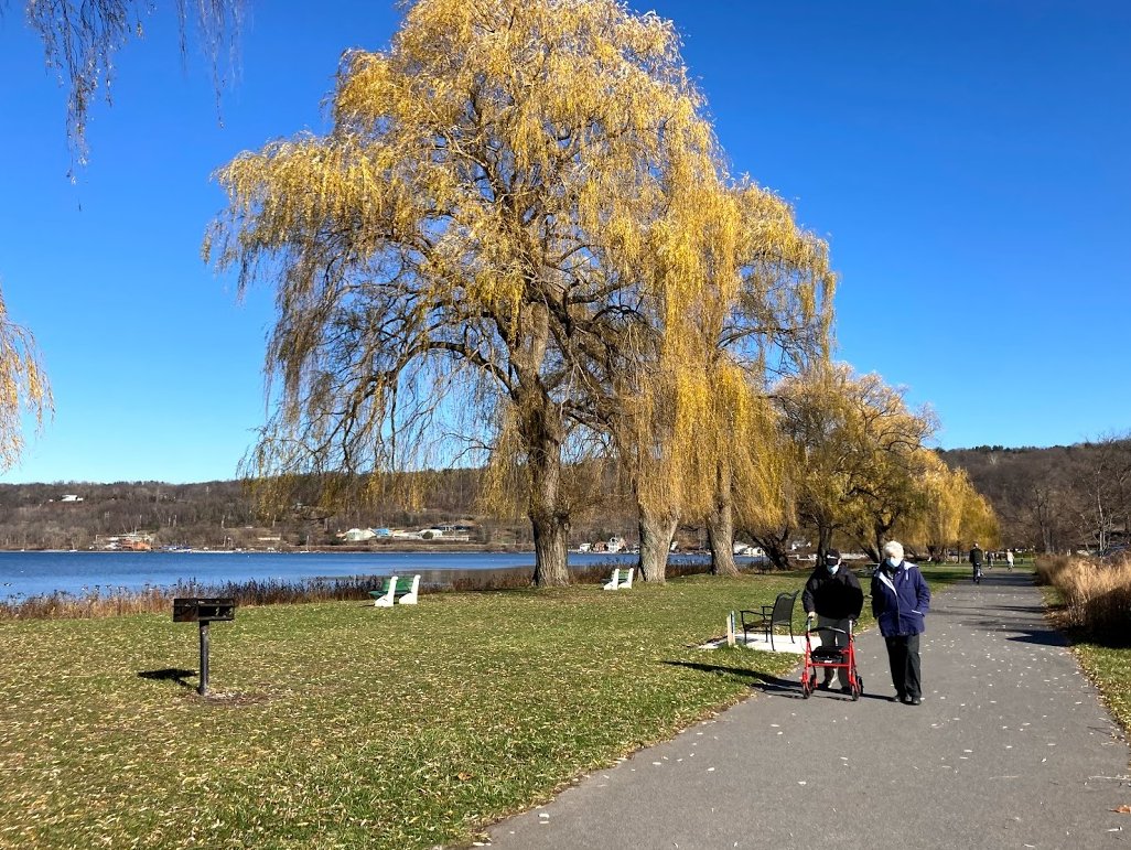 Two people on a paved trail with a lake in the background