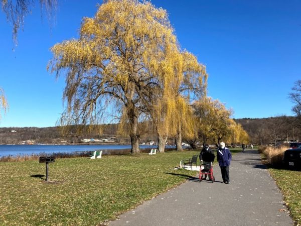 Two people walking on a paved trail with a lakeview