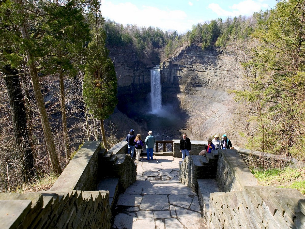 People at an overlook with a tall waterfall in the background